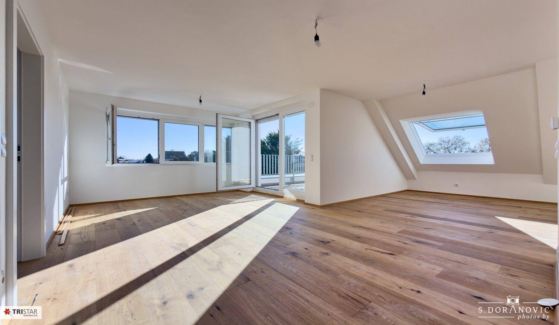 Lichtdurchfluteter Raum mit Holzboden, Dachfenster und Zugang zur Terrasse.
