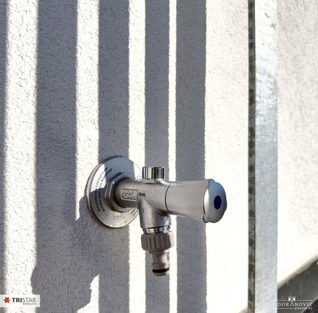 Außenwasserhahn an einer weißen Wand, praktisch für die Gartenbewässerung oder Reinigung.