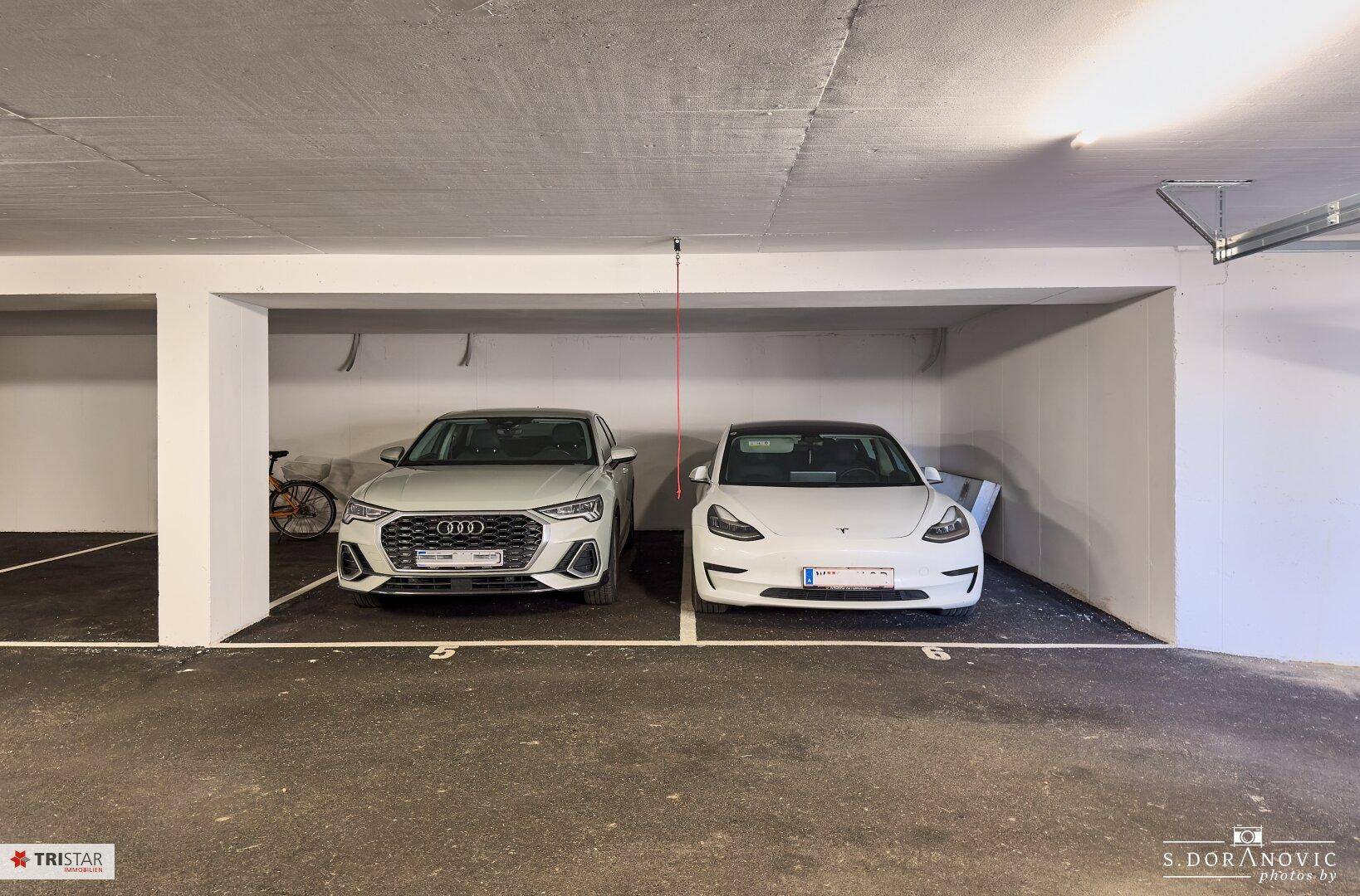 Zwei moderne Autos parken in einem hellen und sauberen Tiefgaragenstellplatz.