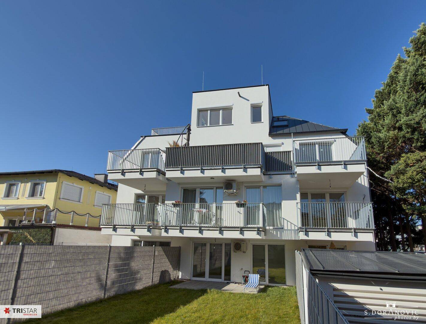 Moderne Wohnanlage mit Balkonen, Terrassen und einem gepflegten Rasenbereich im Freien.