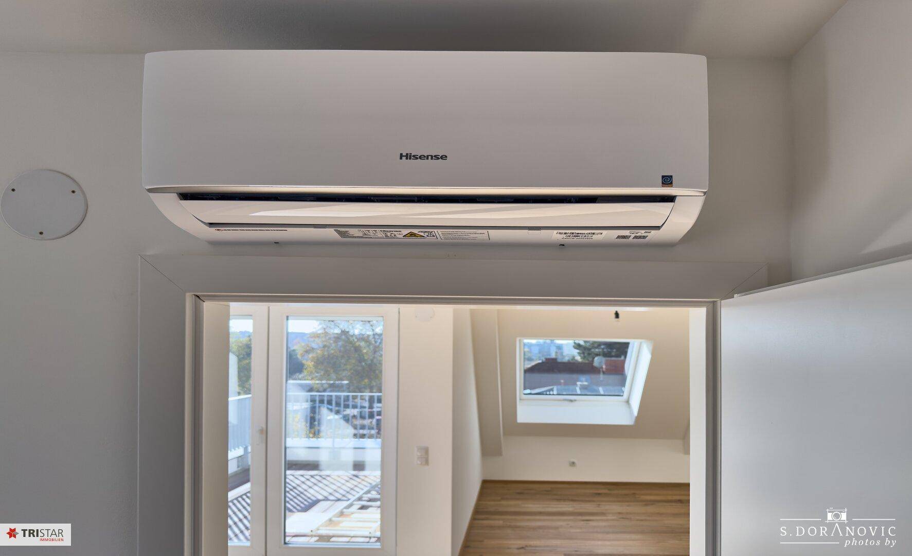 Klimaanlage über einem Türrahmen, dahinter ein Raum mit Holzboden und Fenster.