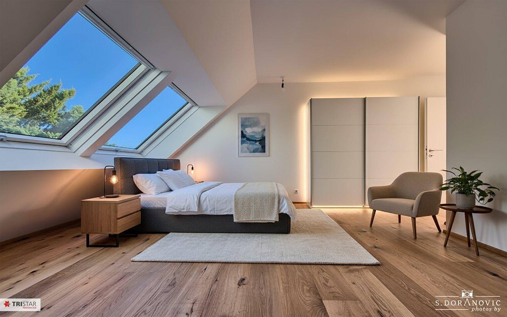 Helles Schlafzimmer mit Holzboden, Dachfenstern und modernem Einbauschrank.