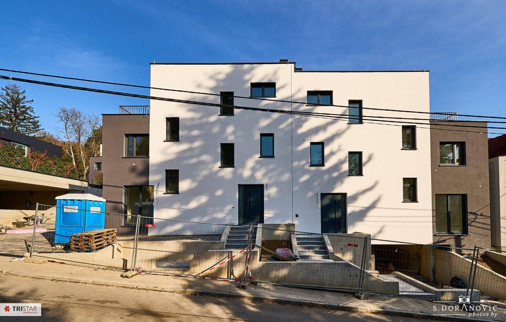 Fassade eines modernen Neubaus mit weißer und grauer Farbgebung während der Bauphase.