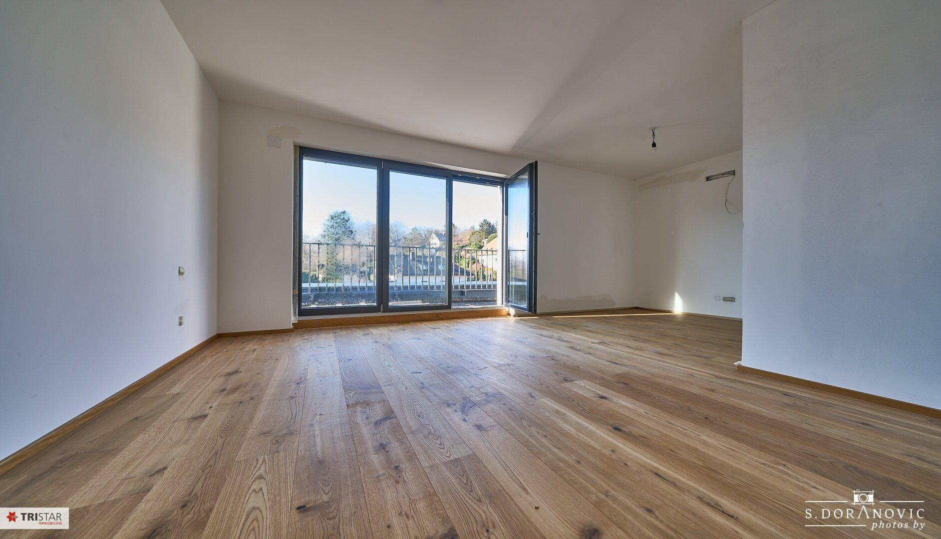 Geräumiges, helles Zimmer mit Holzboden und Zugang zu einem Balkon mit schöner Aussicht.