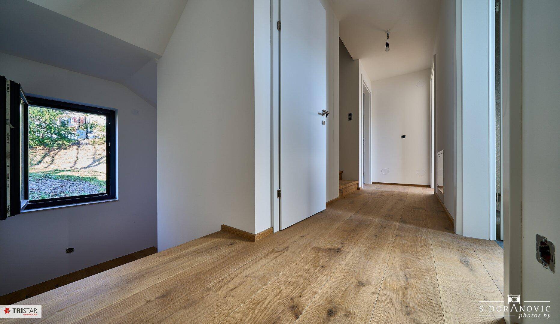 Heller Flur mit Holzboden und mehreren Türen, der zu verschiedenen Räumen führt.