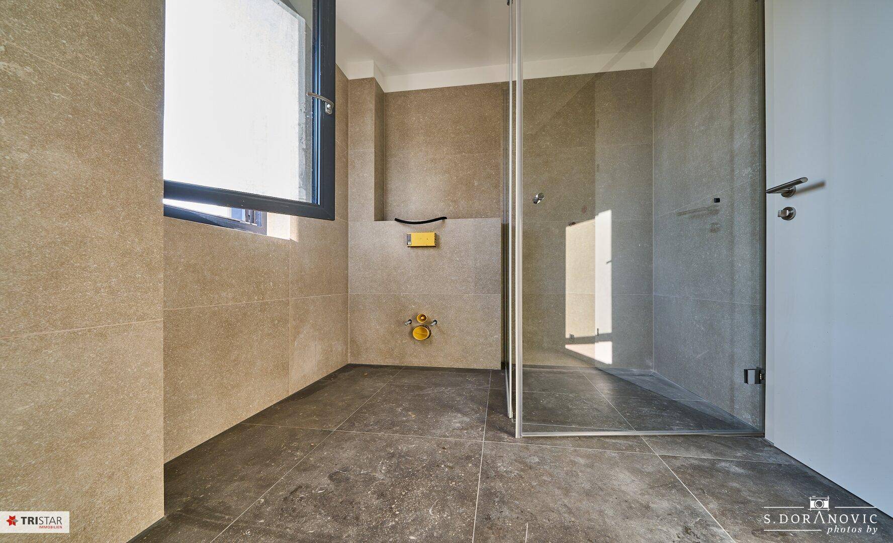 Helles Badezimmer mit modernen Fliesen, ebenerdiger Dusche und Fenster für Tageslicht.