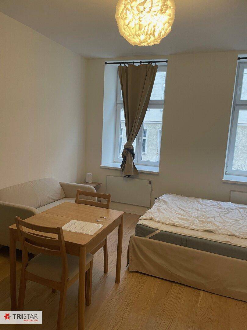 Gemütlicher Wohnbereich mit Sofa, Esstisch und Bett, durch zwei Fenster gut belichtet und gepflegt.