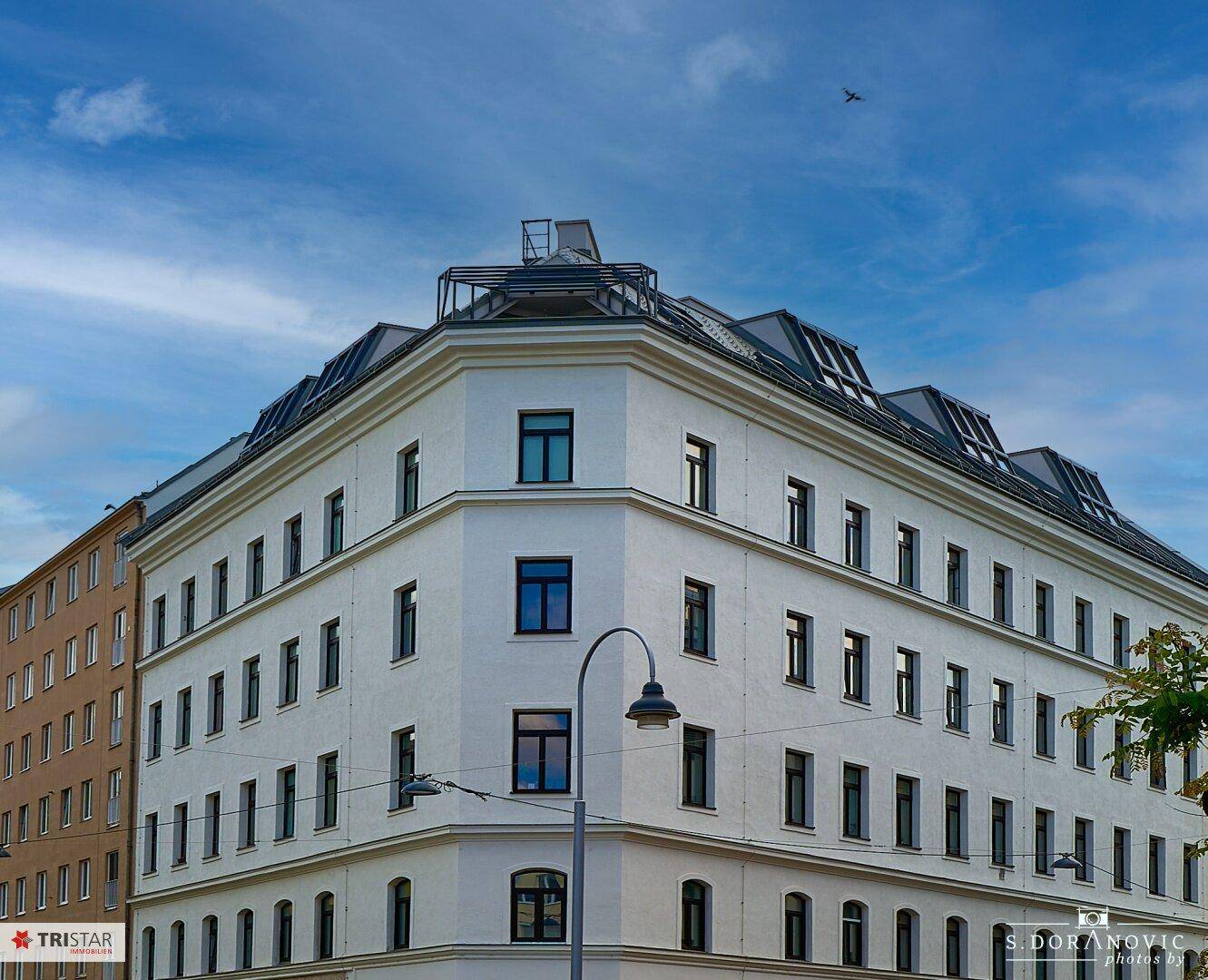Elegante Fassade eines Eckgebäudes mit vielen Fenstern und klassischer Architektur.