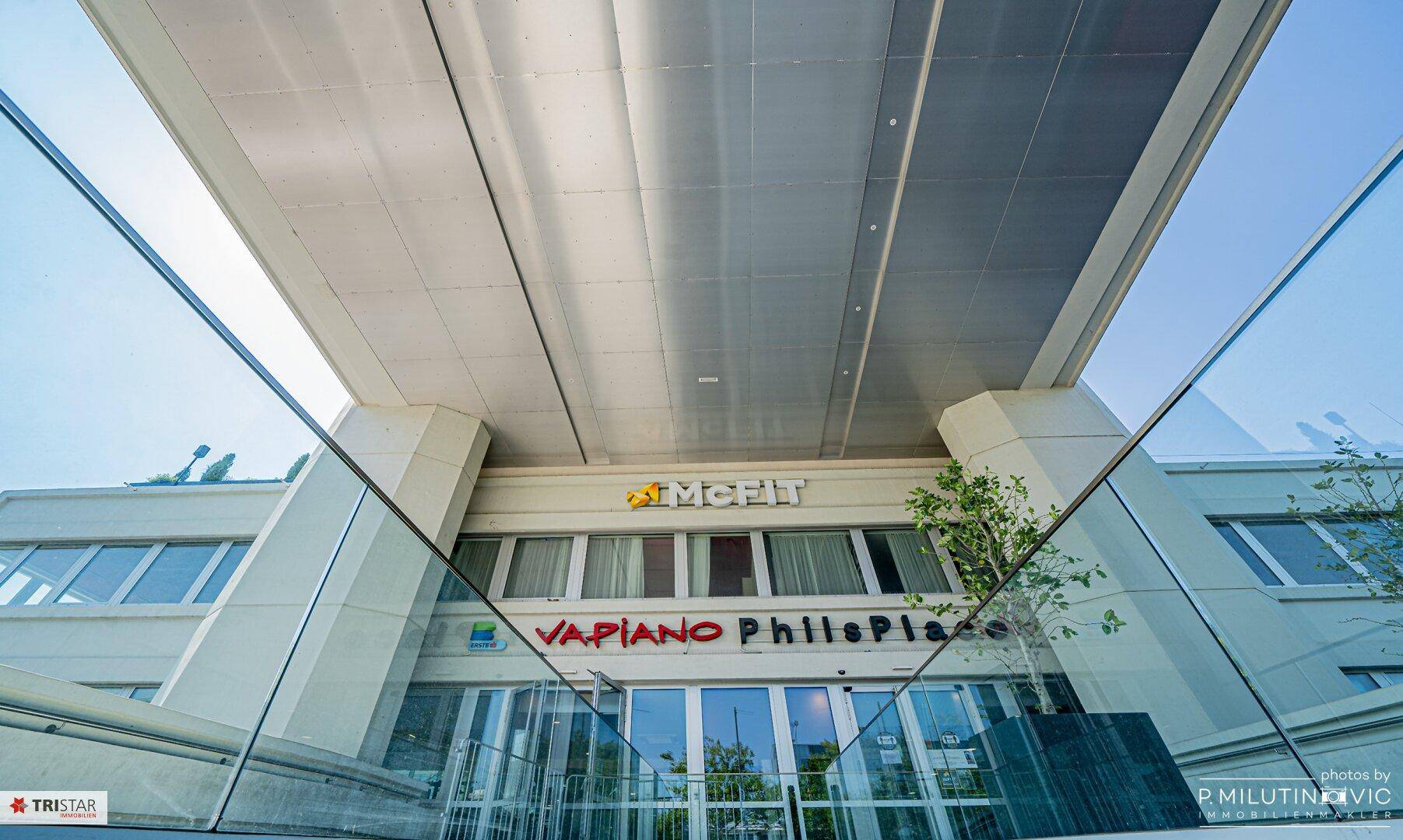 Fassade eines Gebäudes mit Geschäften wie Vapiano und PhillsPlace.