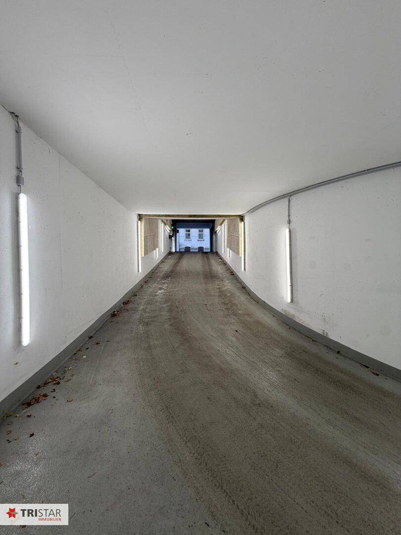 Gerade Zufahrtsrampe einer Tiefgarage, die zum Ausgang mit Tageslicht führt.
