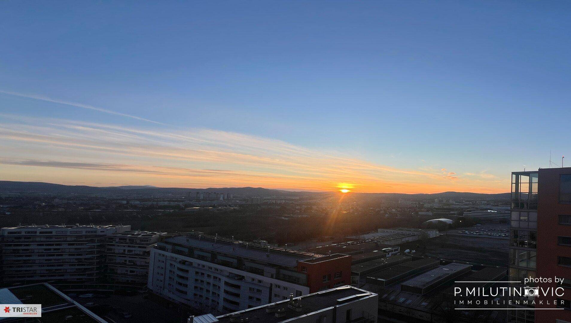 Malerischer Sonnenuntergang über der Stadt mit weitem Blick auf die umliegende Landschaft und Berge.