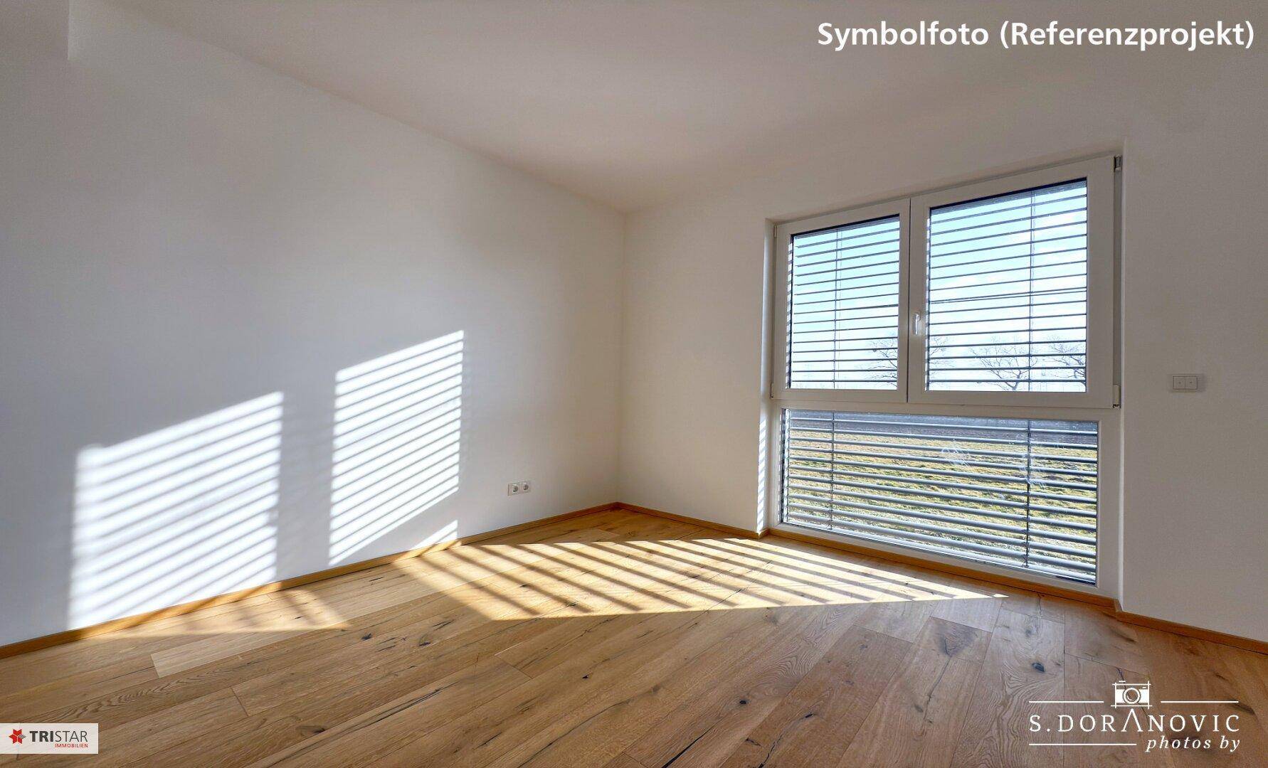 Helles Schlafzimmer mit Holzboden und großem Fenster, das viel Sonnenlicht hereinlässt.