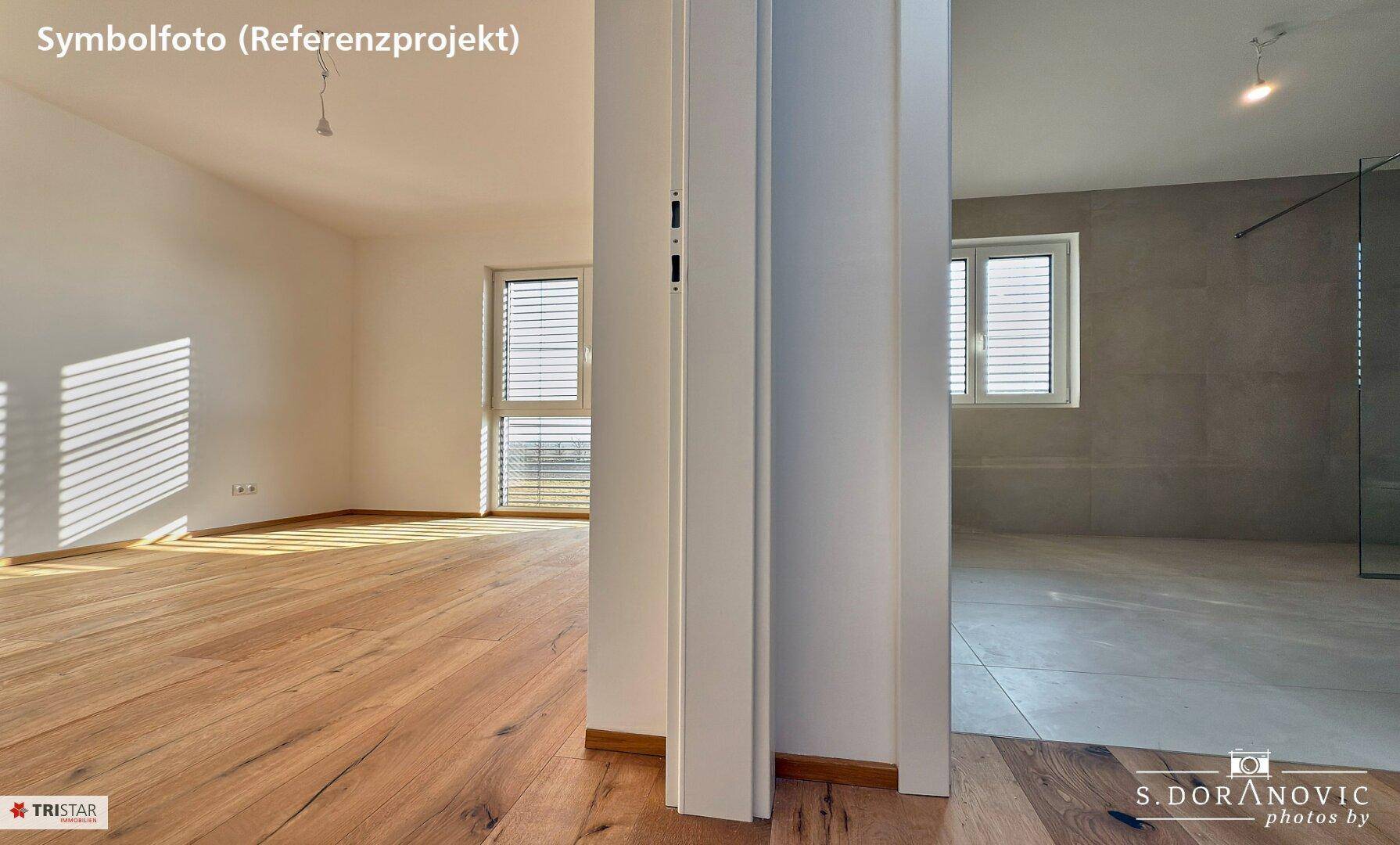 Blick vom Zimmer in ein modernes Badezimmer mit Fliesenboden und begehbarer Dusche.