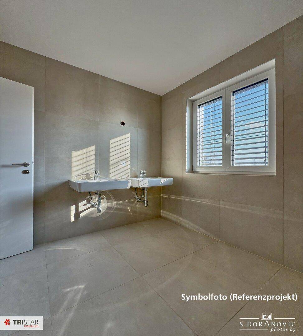 Modernes Badezimmer mit zwei Waschbecken, großen Fliesen und Fenster für viel Tageslicht.