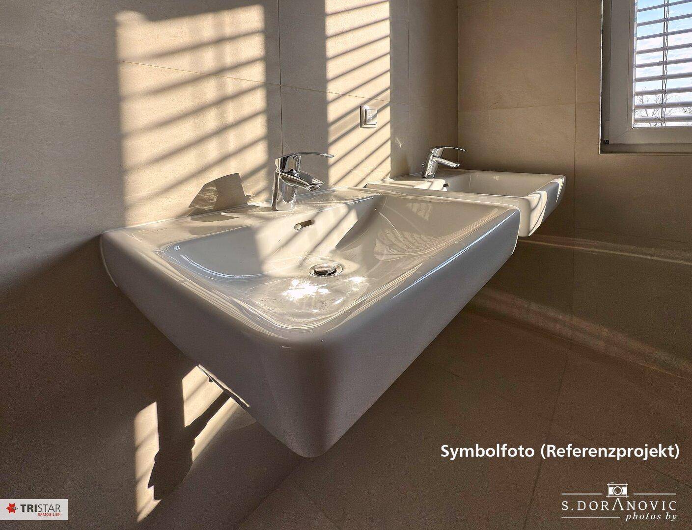 Modernes Badezimmer mit zwei Waschbecken, großen Fliesen und Fenster für Tageslicht.