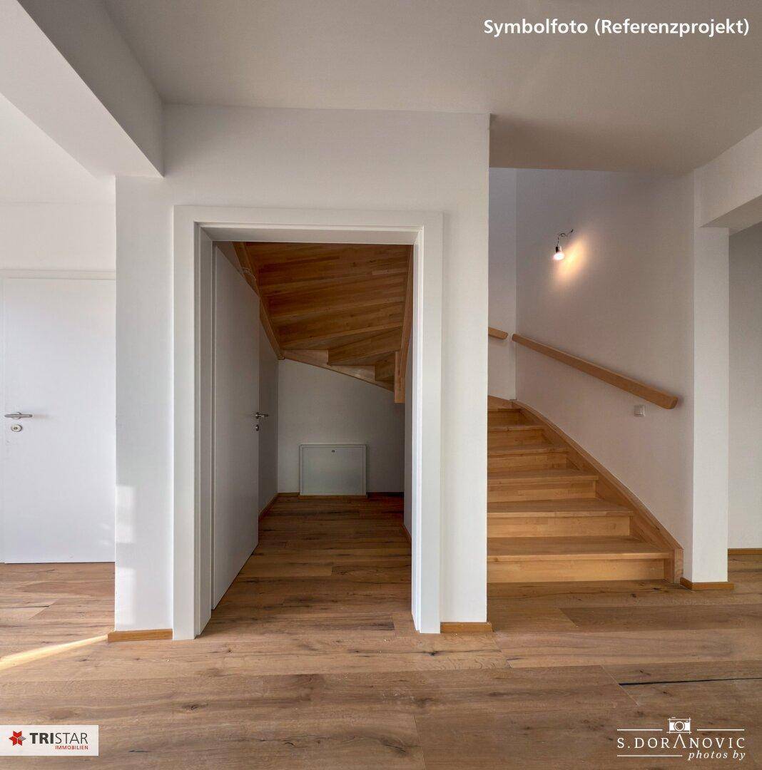 Heller Flur mit Holzboden und einer eleganten Holztreppe, die in die oberen Stockwerke führt.