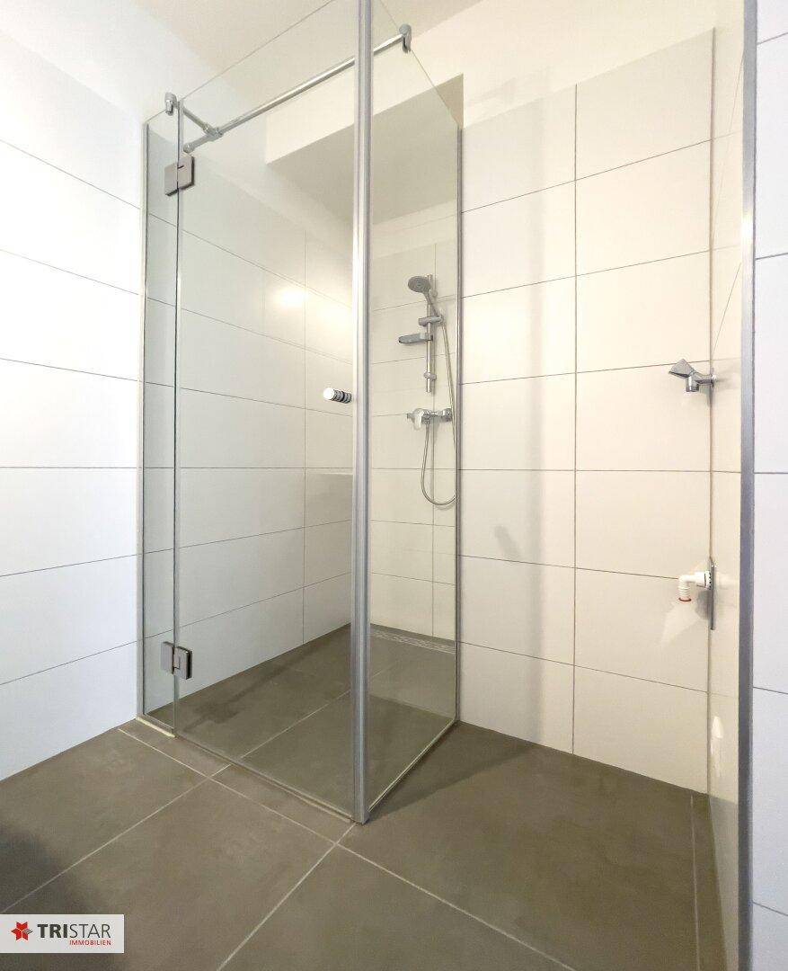 Helle Duschkabine mit Glaswänden und modernen Fliesen im Badezimmer.