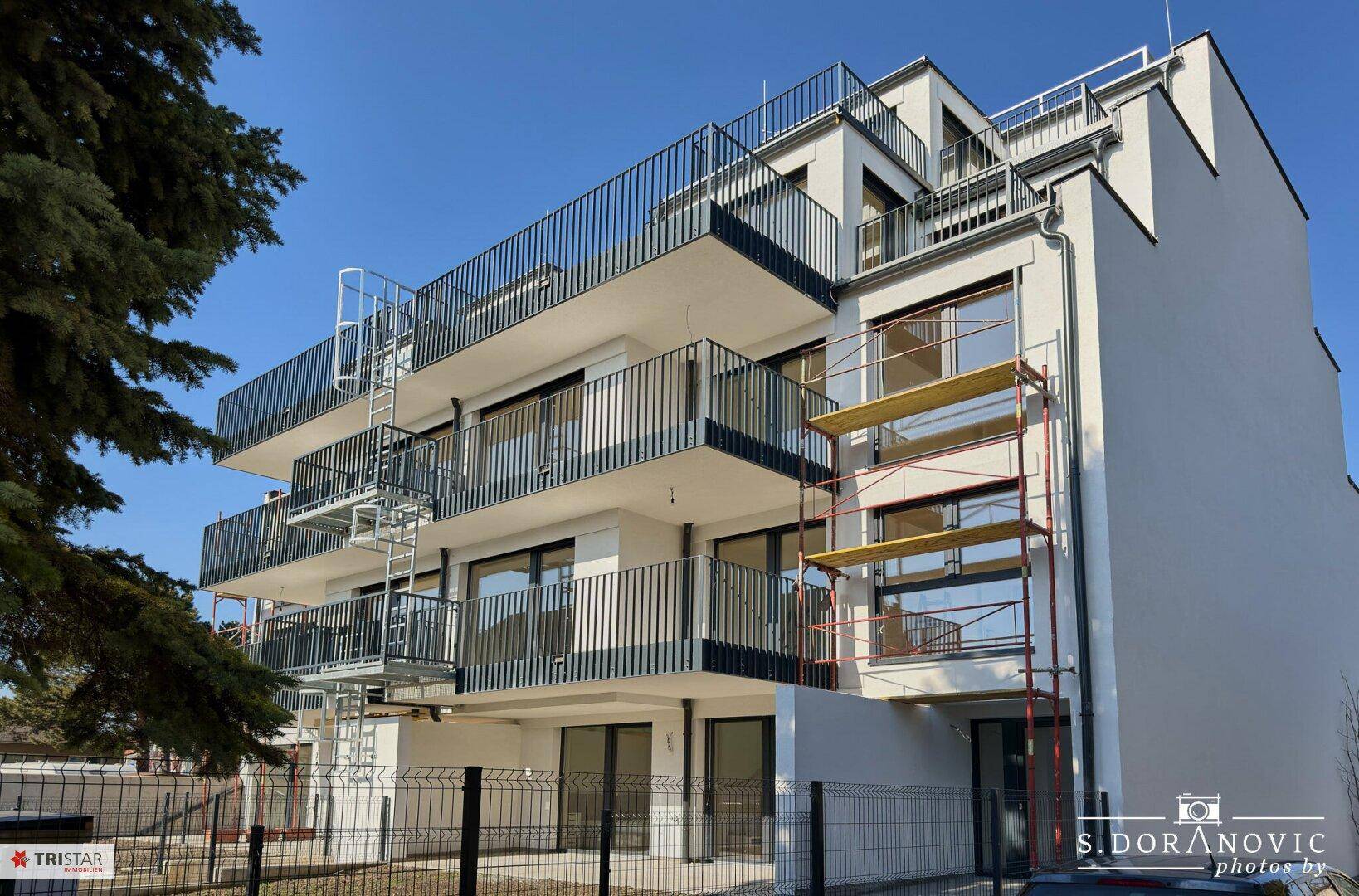 Moderne Wohnanlage mit mehreren Balkonen und Gerüsten, die auf Fertigstellung hindeuten.