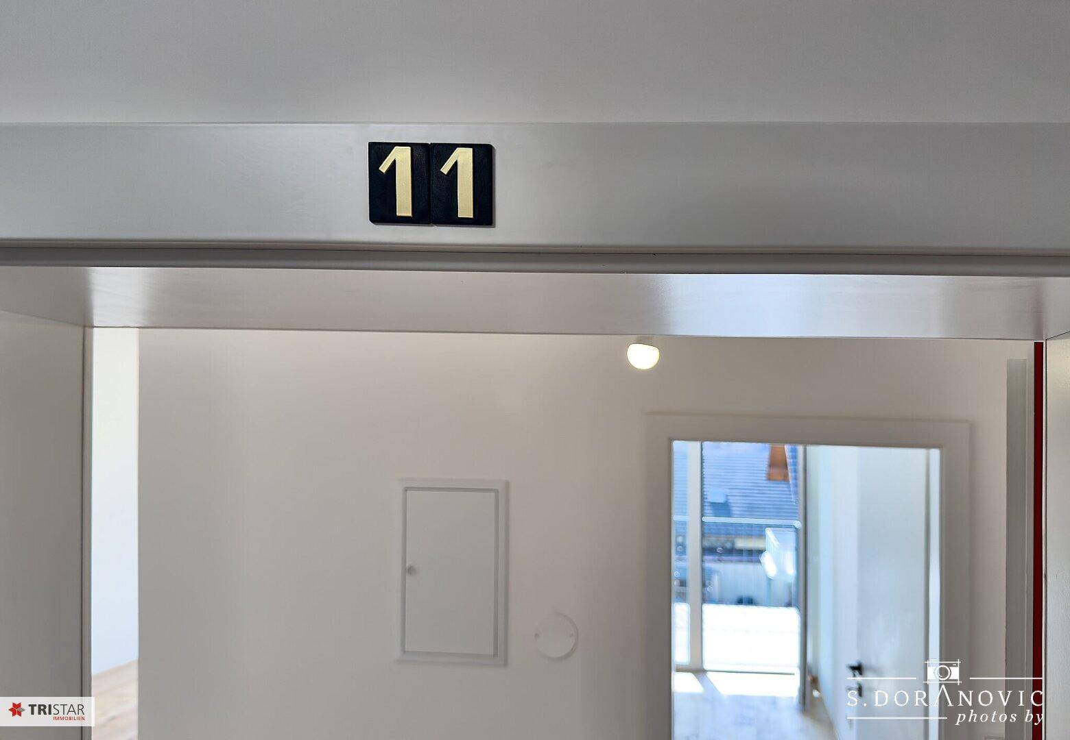 Eingangsbereich einer Wohnung mit der Nummer 11, führt in helle Räume.