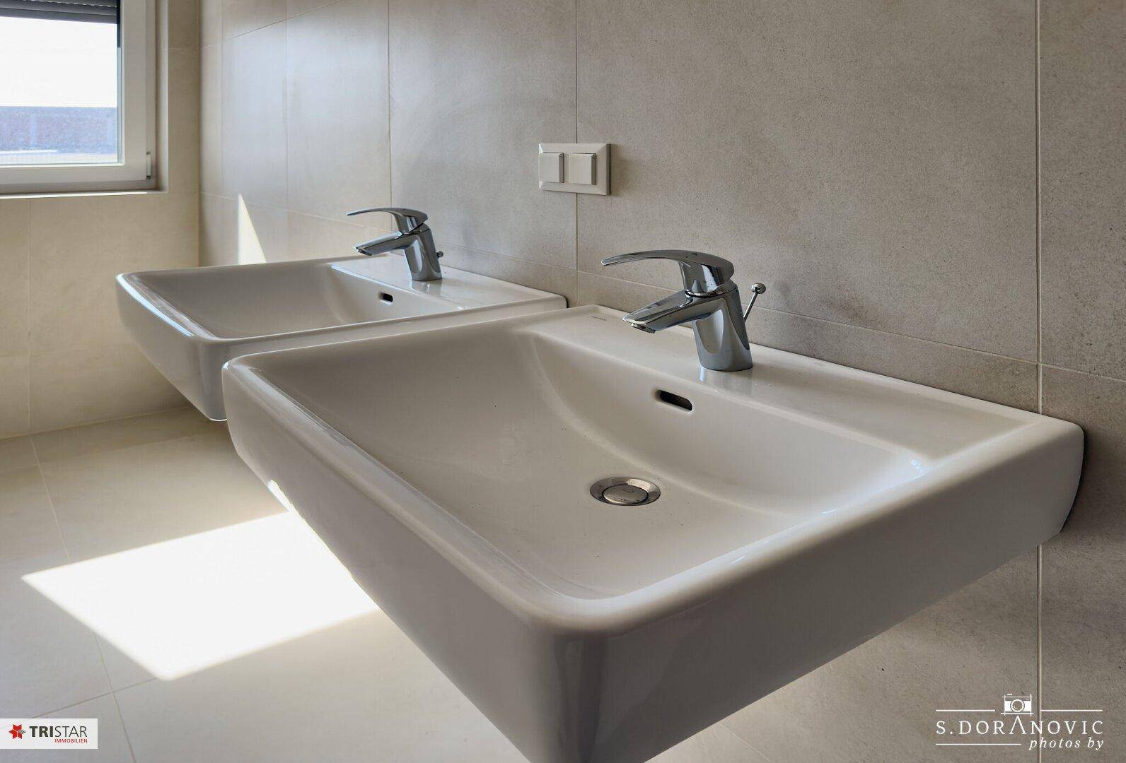 Detailansicht von zwei modernen Waschbecken in einem hellen Badezimmer.
