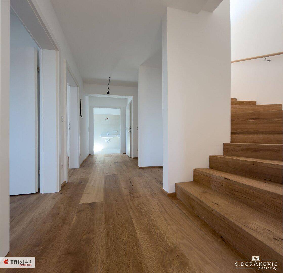 Heller Flur mit Eichenparkett und eleganter Holztreppe.