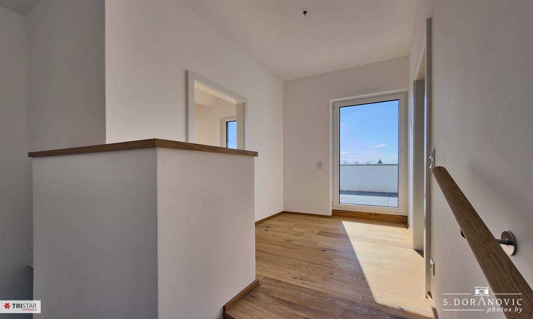 Heller Flurbereich mit Holzboden, Fenster und Zugang zur Dachterrasse.