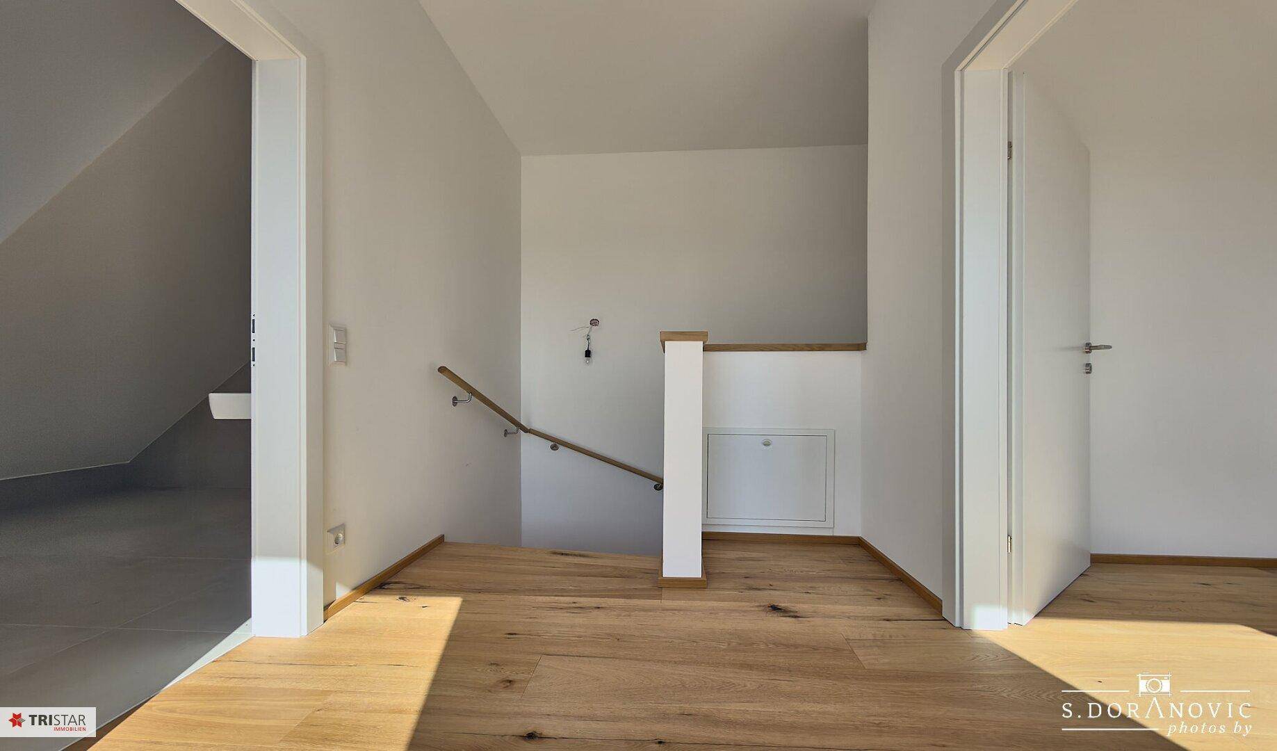 Heller Flurbereich im Dachgeschoss mit Holztreppe und Holzboden.