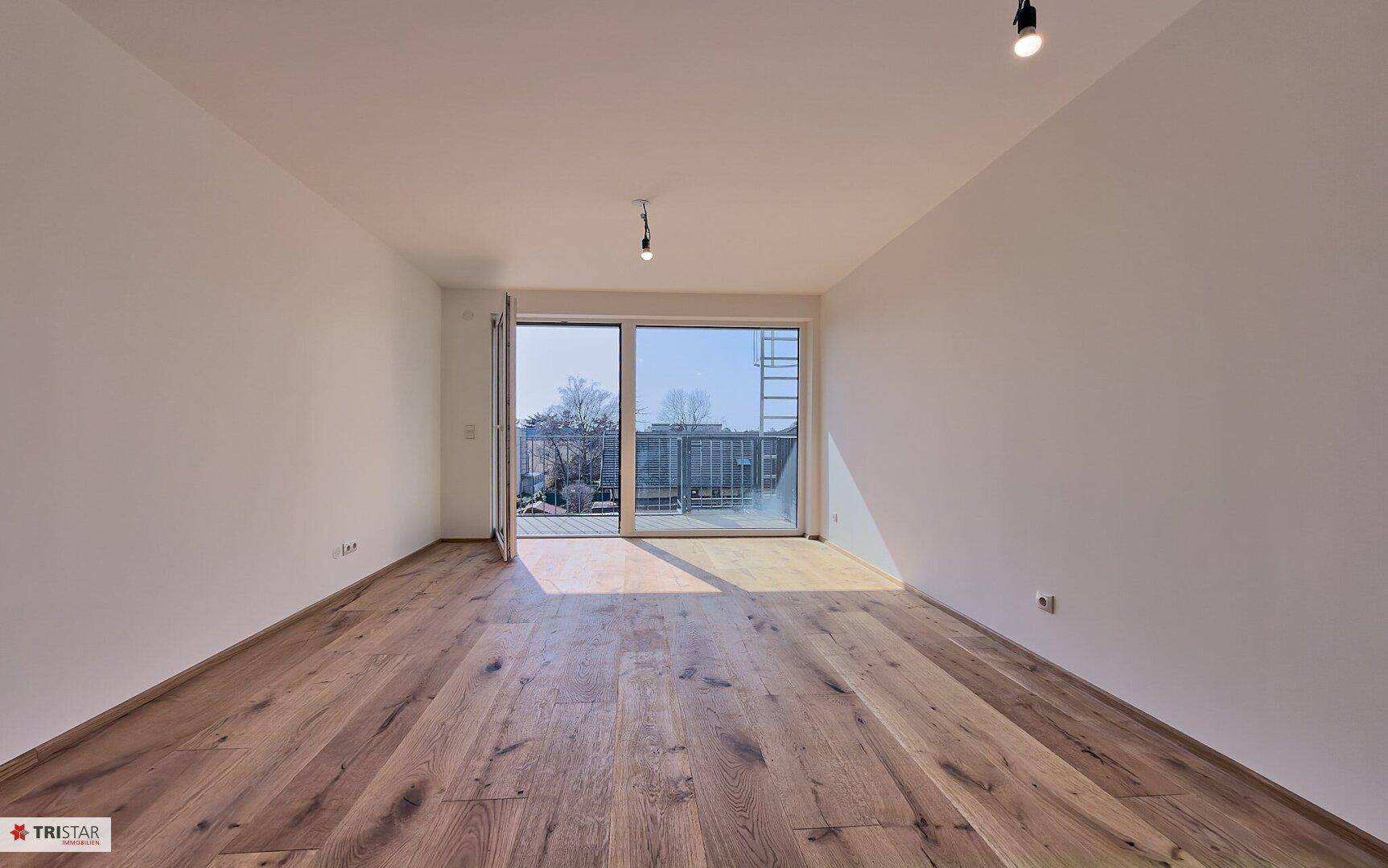 Geräumiges Schlafzimmer mit Holzboden und Zugang zu einem sonnigen Balkon.