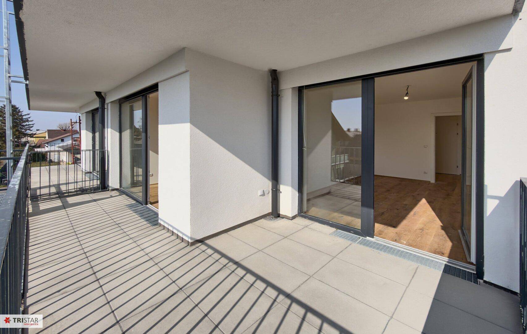 Geräumiger Balkon mit Fliesenboden und Blick auf die Umgebung, ideal für entspannte Stunden im Freien.