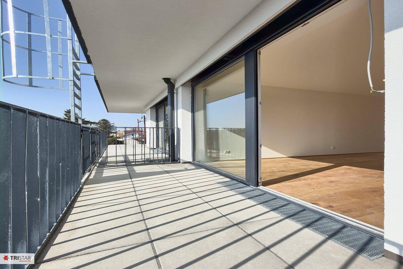 Langer Balkon mit Fliesenboden und Metallgeländer, der viel Platz im Freien bietet.