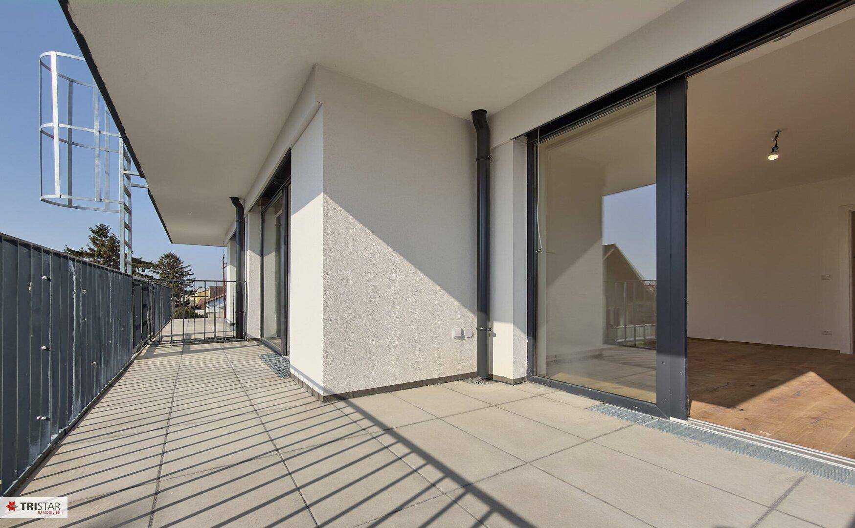 Geräumiger Balkon mit Fliesenboden und moderner Fassade, ideal für entspannte Stunden im Freien.