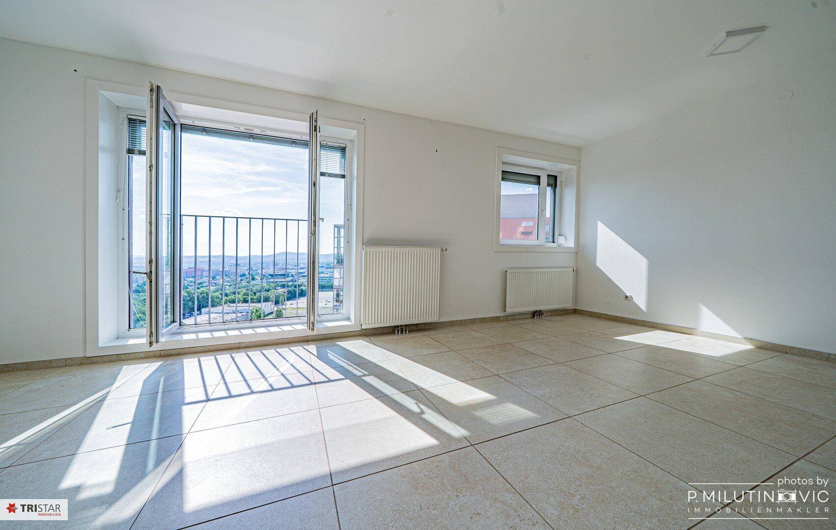 Heller, leerer Raum mit Fliesenboden und Zugang zu einem französischen Balkon.