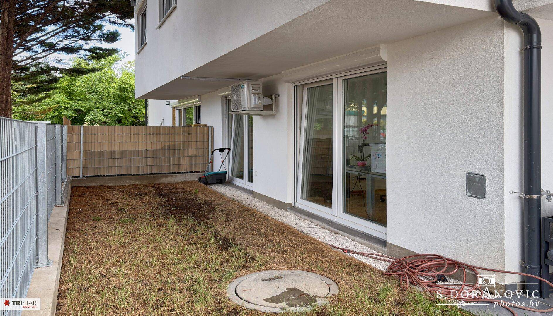 Kleiner Gartenbereich neben der Terrasse mit Rasenfläche und Zugang zum Innenbereich.