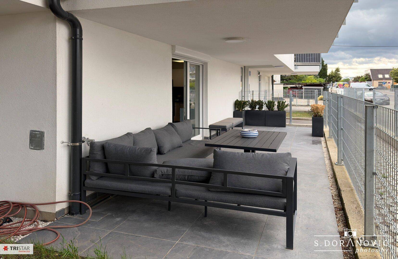 Geräumige Terrasse mit modernen Outdoor-Möbeln und Blick ins Grüne.