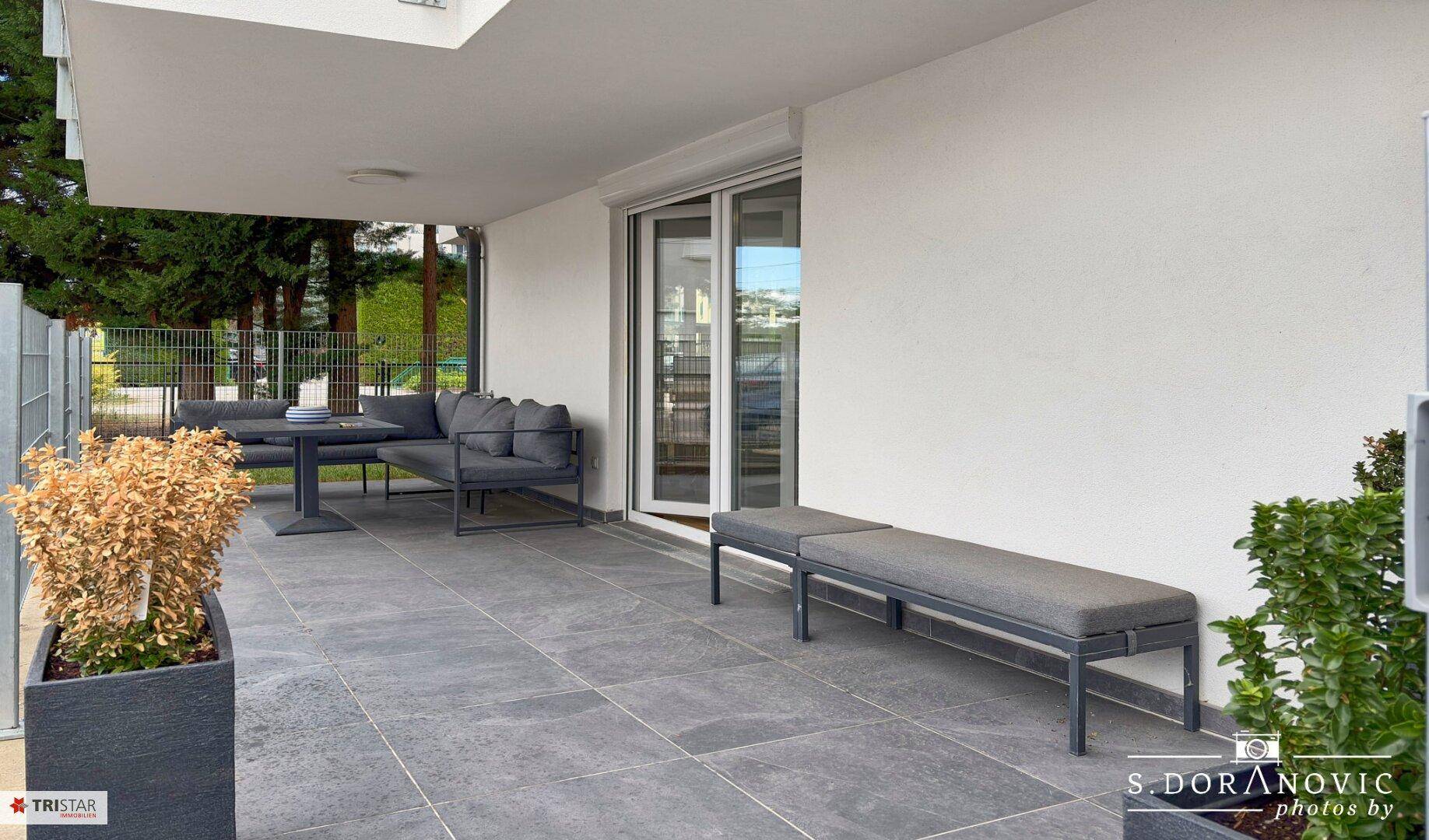 Breite Terrasse mit Sitzgelegenheiten und Pflanzenkübeln, ideal zum Entspannen.