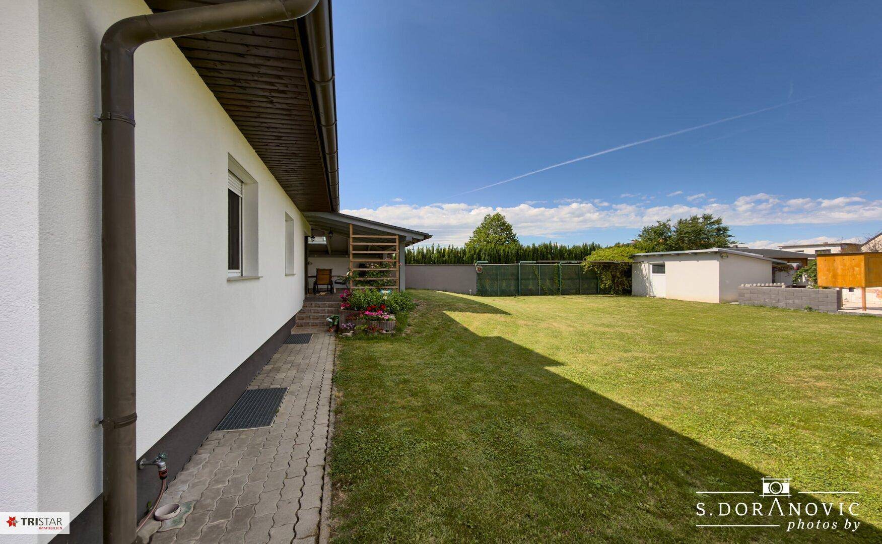 Lange Rasenfläche im Garten entlang der Hauswand mit Blick in die weite Landschaft.