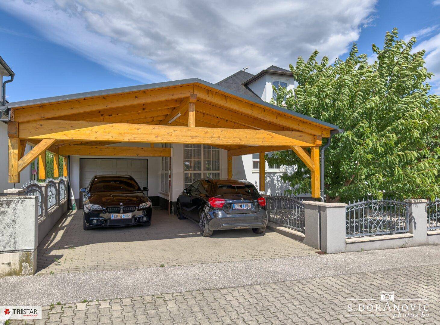 Geräumiger Holzcarport mit zwei Stellplätzen und integrierter Garage vor dem Haus.