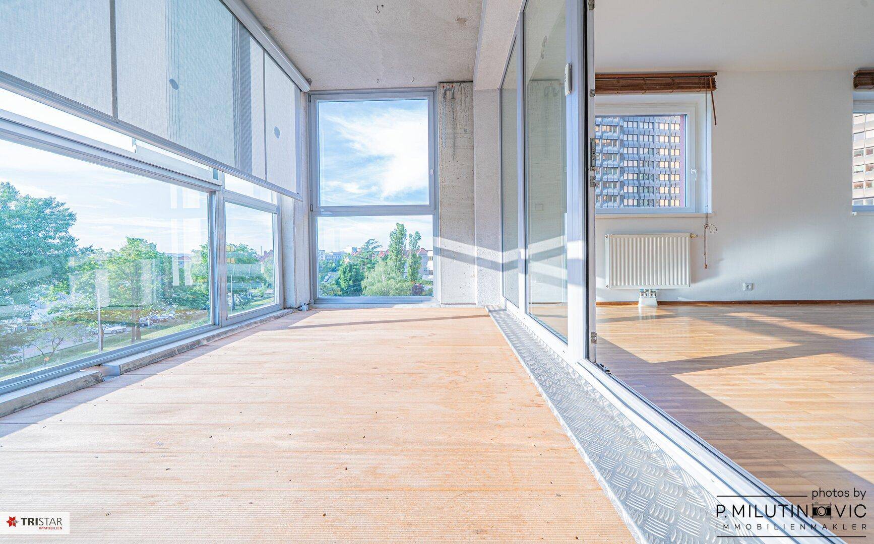 Verglaste Loggia mit Holzboden und weitem Blick ins Grüne.