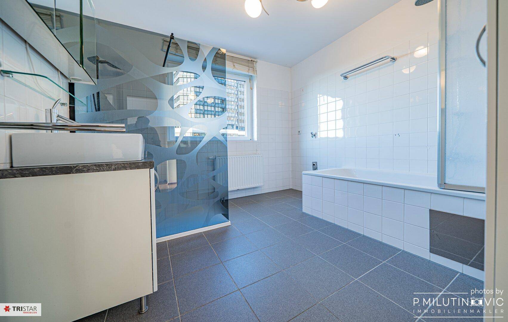 Geräumiges Badezimmer mit Badewanne, Dusche und modernem Design der Duschwand.