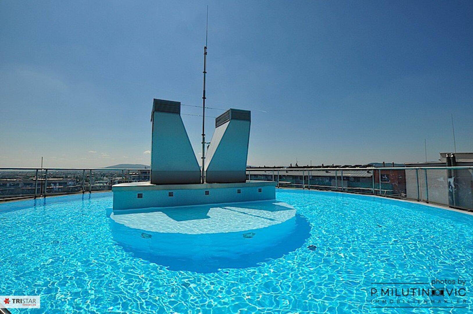 Dachpool mit klarem blauen Wasser und moderner Architektur im Hintergrund.