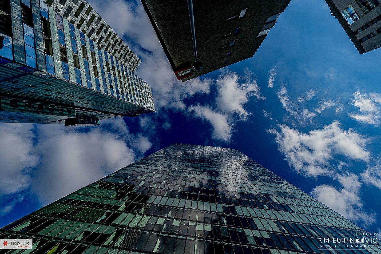 Mehrere moderne Hochhäuser mit Glasfassaden, die sich gegen den blauen Himmel abzeichnen.