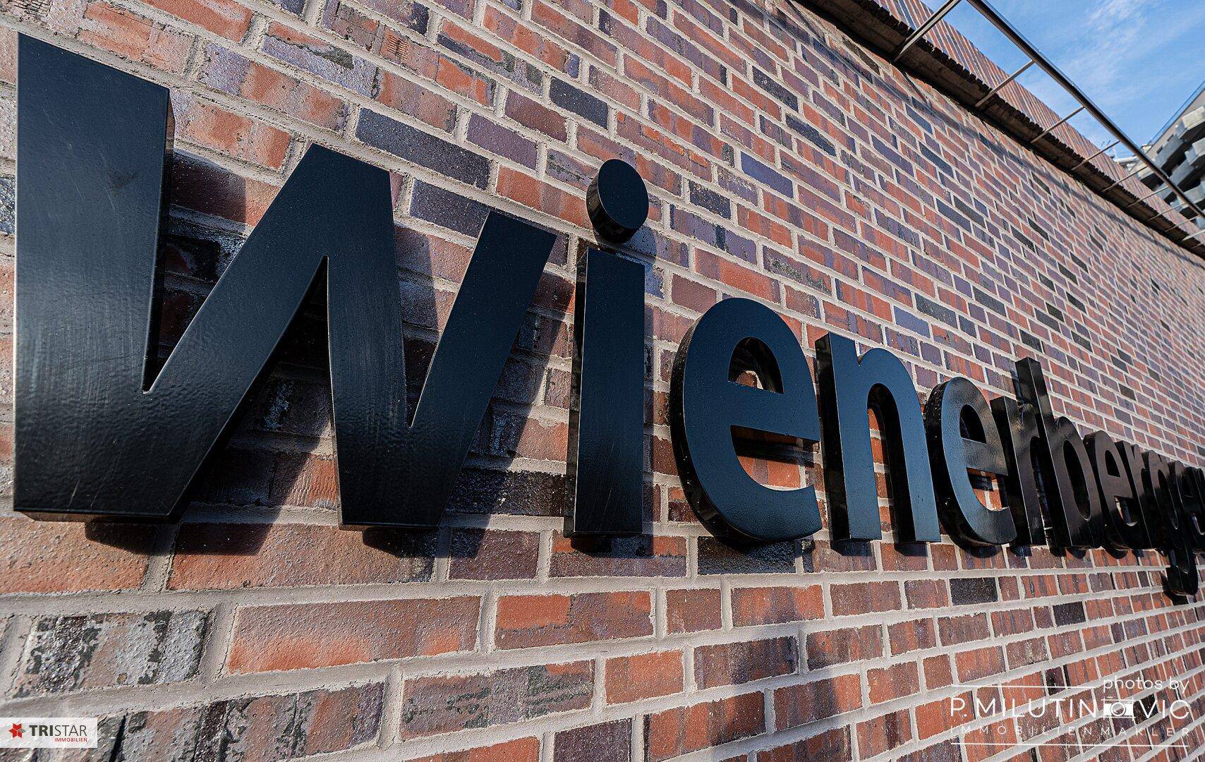 Schriftzug "Wienerberg" an einer Ziegelwand, Teil der lokalen Architektur.