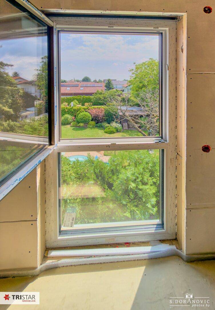 Große Fenster bieten einen weiten Blick auf den grünen Garten und die Nachbarschaft.