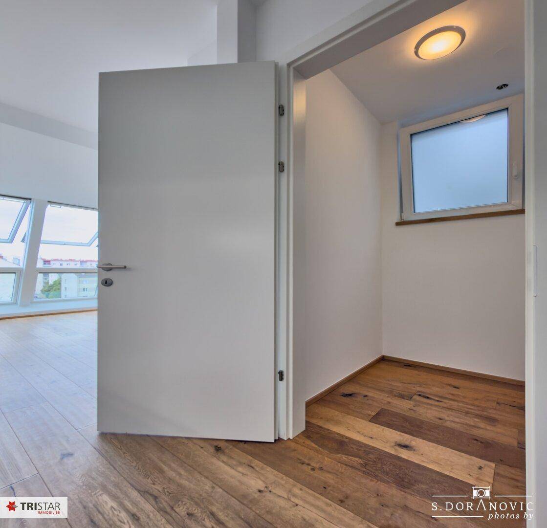 Kleiner Abstellraum mit Fenster und Holzboden, ideal für zusätzlichen Stauraum.
