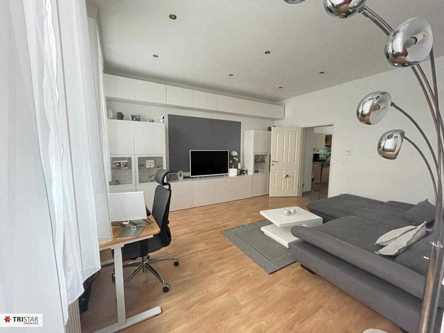 Gemütliches Wohnzimmer mit Sofa, Schreibtisch und integrierter Medieneinheit.