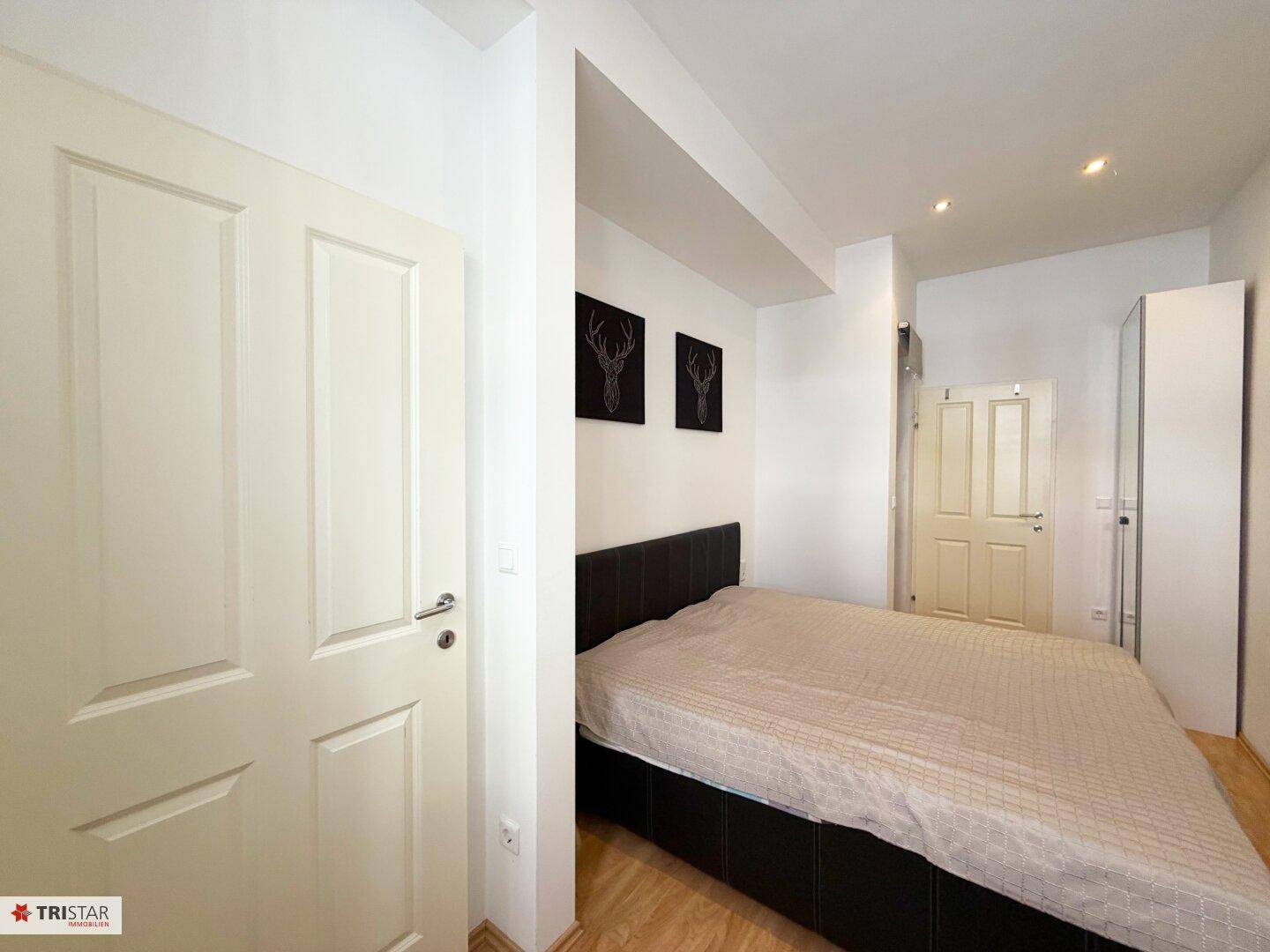 Schlafzimmer mit Doppelbett, weißer Tür und einem Kleiderschrank.
