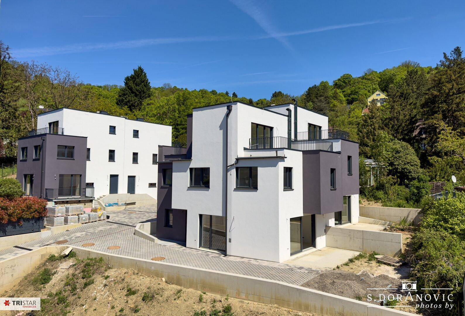 Moderne Wohnanlage mit mehreren Neubauten in zeitgenössischer Architektur, eingebettet in grüne Umgebung.