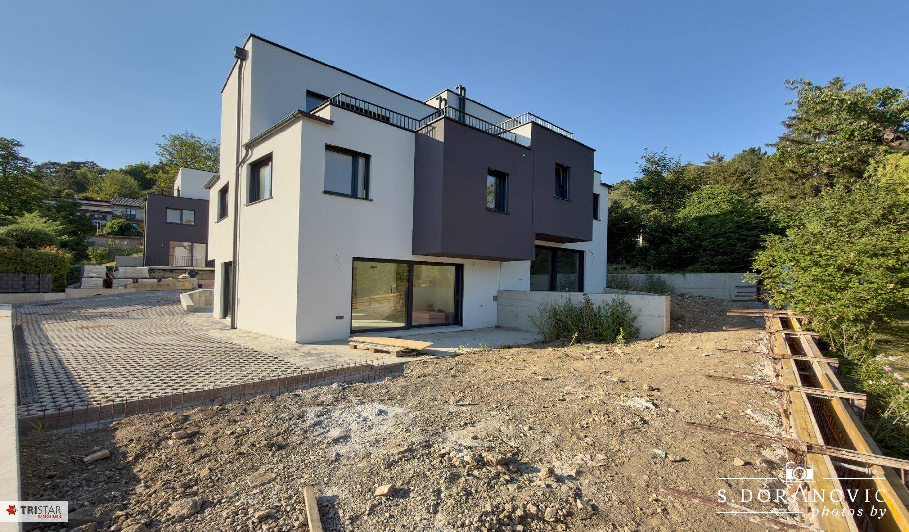 Neubau mit moderner Architektur, weißer und grauer Fassade und noch unfertigem Außenbereich.
