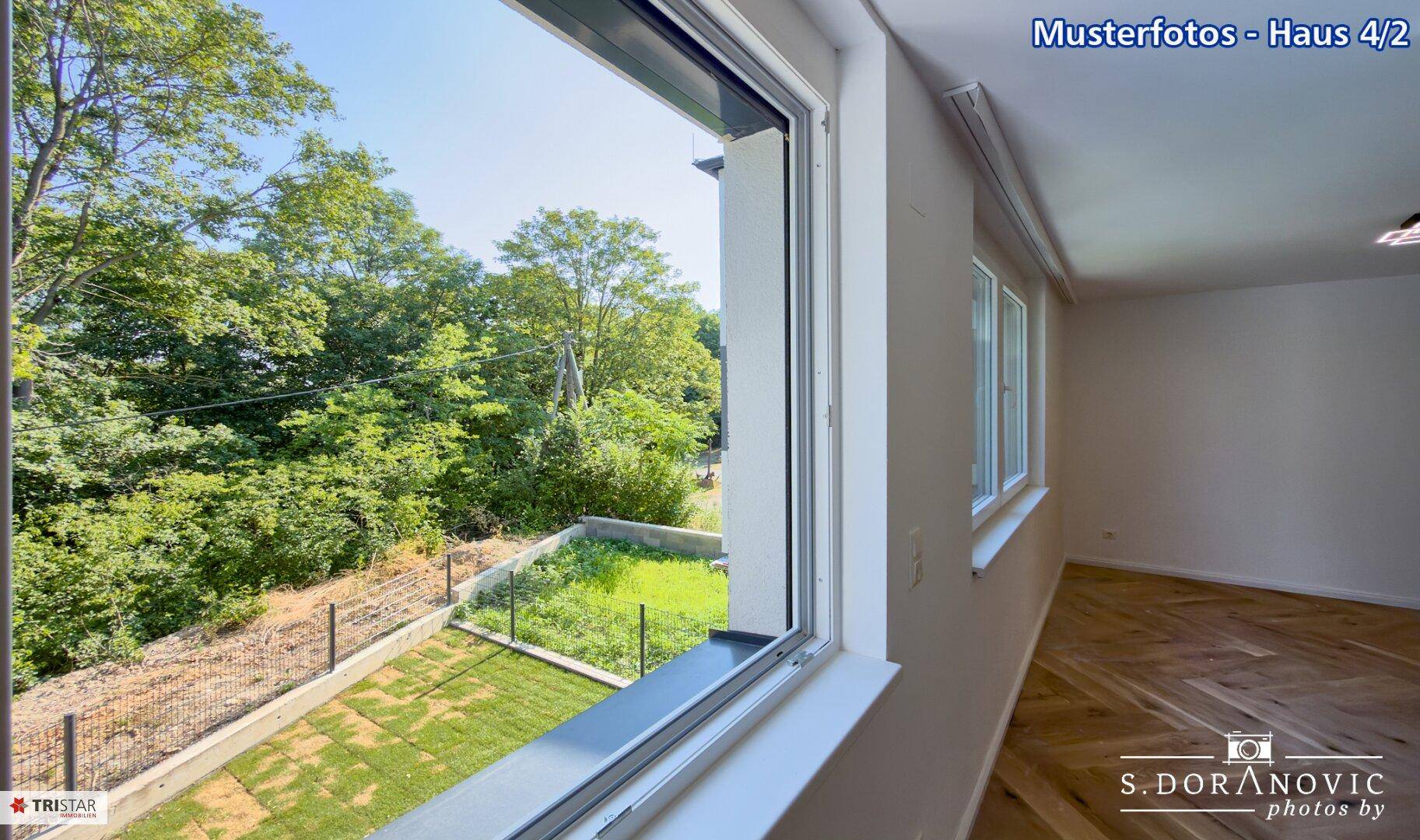 Heller Innenraum mit geöffnetem Fenster, das einen weiten Blick auf den grünen Garten bietet.
