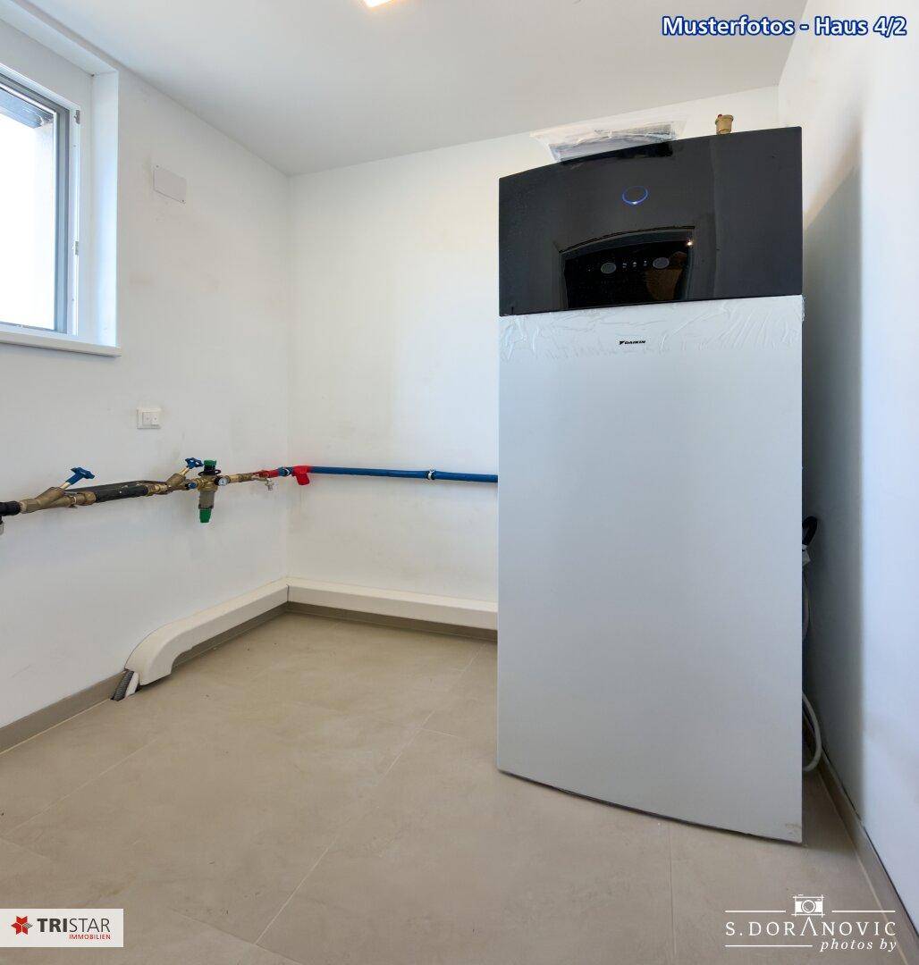 Funktionaler Hauswirtschaftsraum mit moderner Wärmepumpe und sichtbaren Installationen.